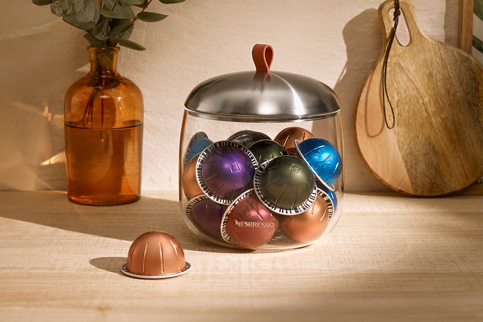 A jar of Nespresso Vertuo coffee capsules on a kitchen top.